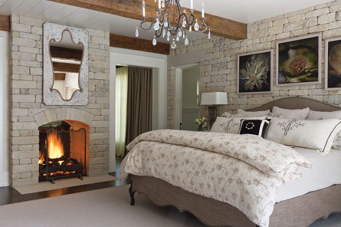 bedroom with rock walls and a fireplace
