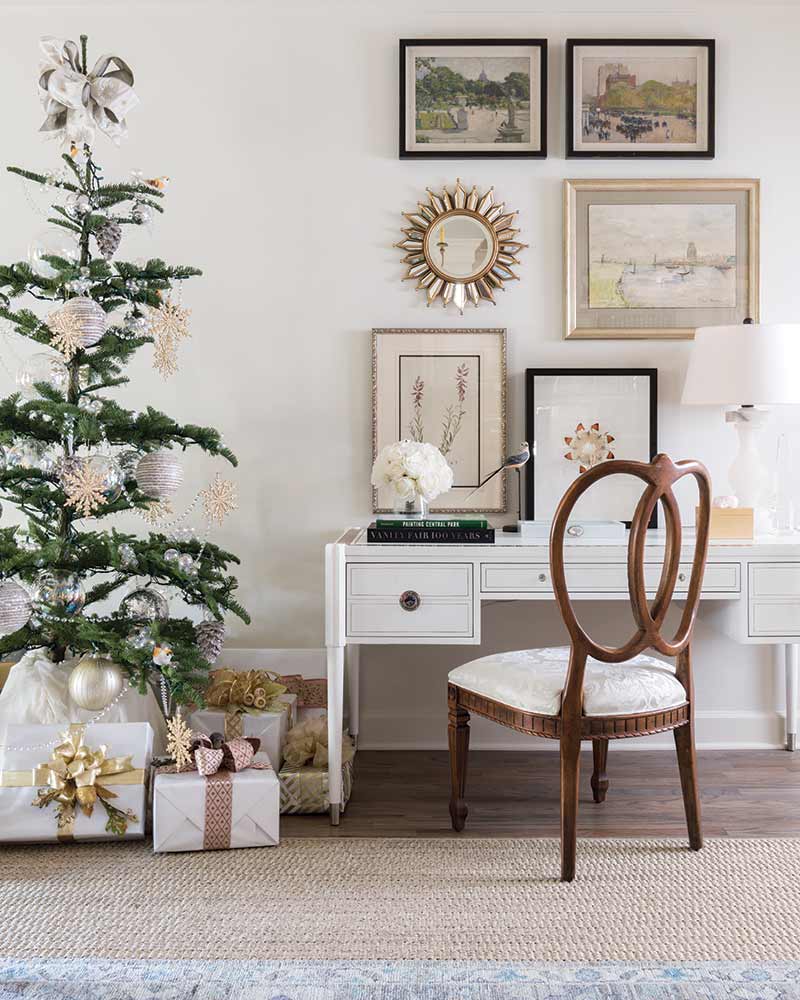 Christmas tree and presents next to white desk and gallery wall