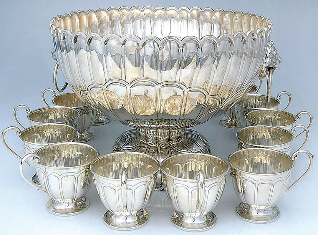 silver punch bowl surrounded by cups